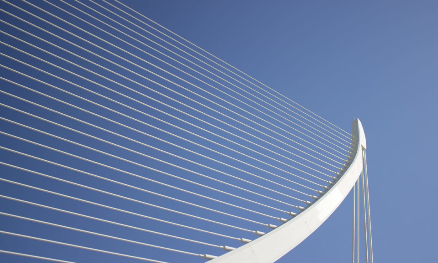 Close-up of a modern white cable-stayed bridge structure against a clear blue sky