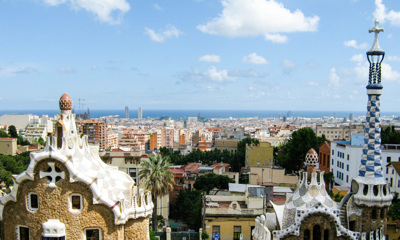 Elevated view of a mosaic-tiled architectural structure with towers overlooking a sprawling coastal city